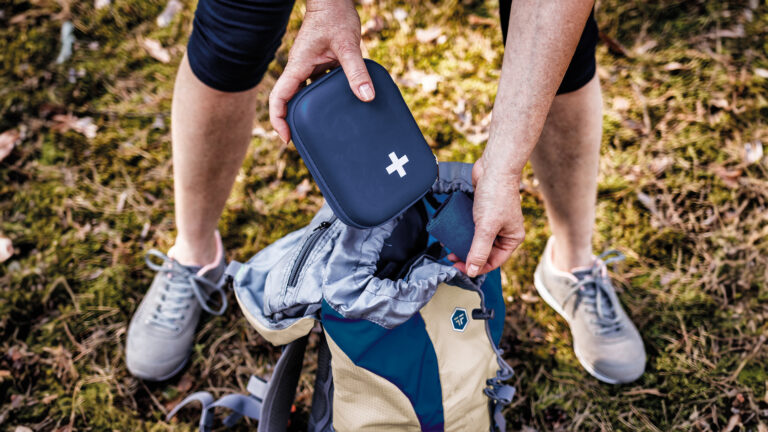 Woman taking out first aid kit from backpack