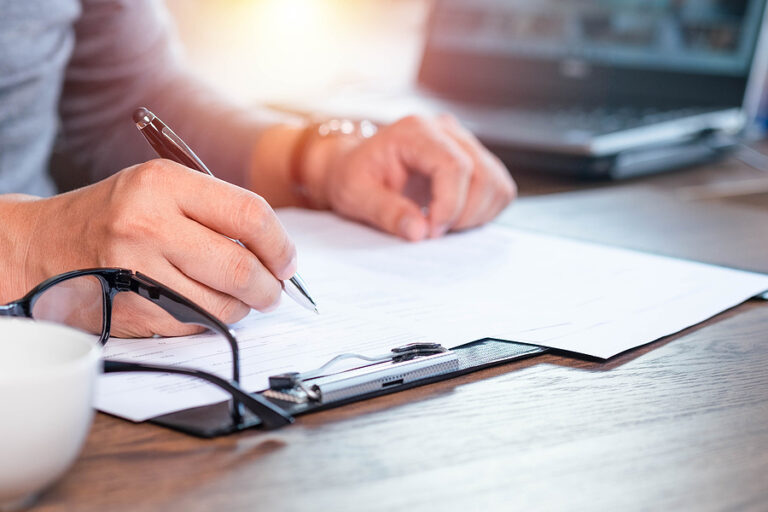 Close-up Of Hand Using Writing Pen With Questionnaire Or Paperwo