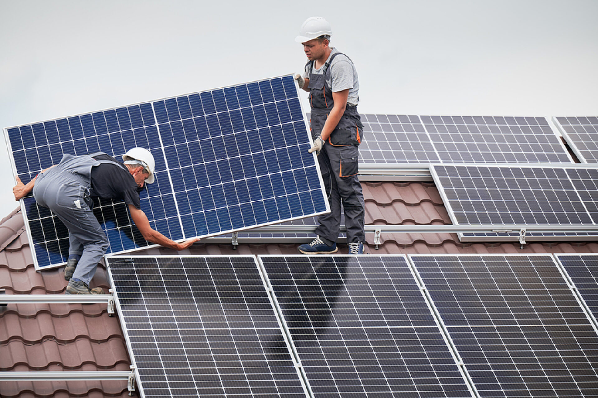 Men Technicians Carrying Photovoltaic Solar Moduls On Roof Of Ho